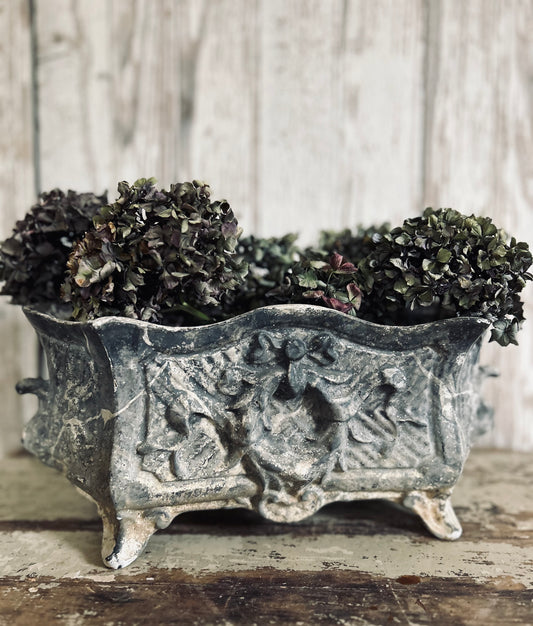 Antique french jardiniere with embossed floral/scroll relief and scroll feet.
