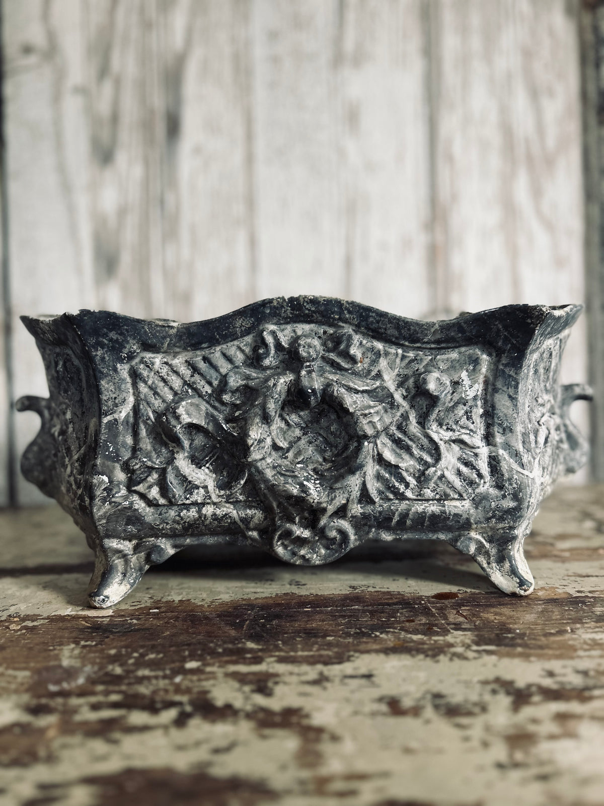 Antique french jardiniere with embossed floral/scroll relief and scroll feet.